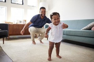Baby Daughter Dancing With Father In Lounge At Home