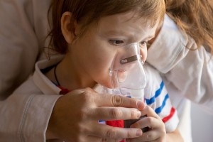 Young woman with son doing inhalation a nebulizer at home