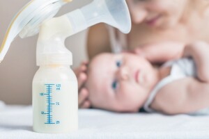 Manual breast pump and milk at background
